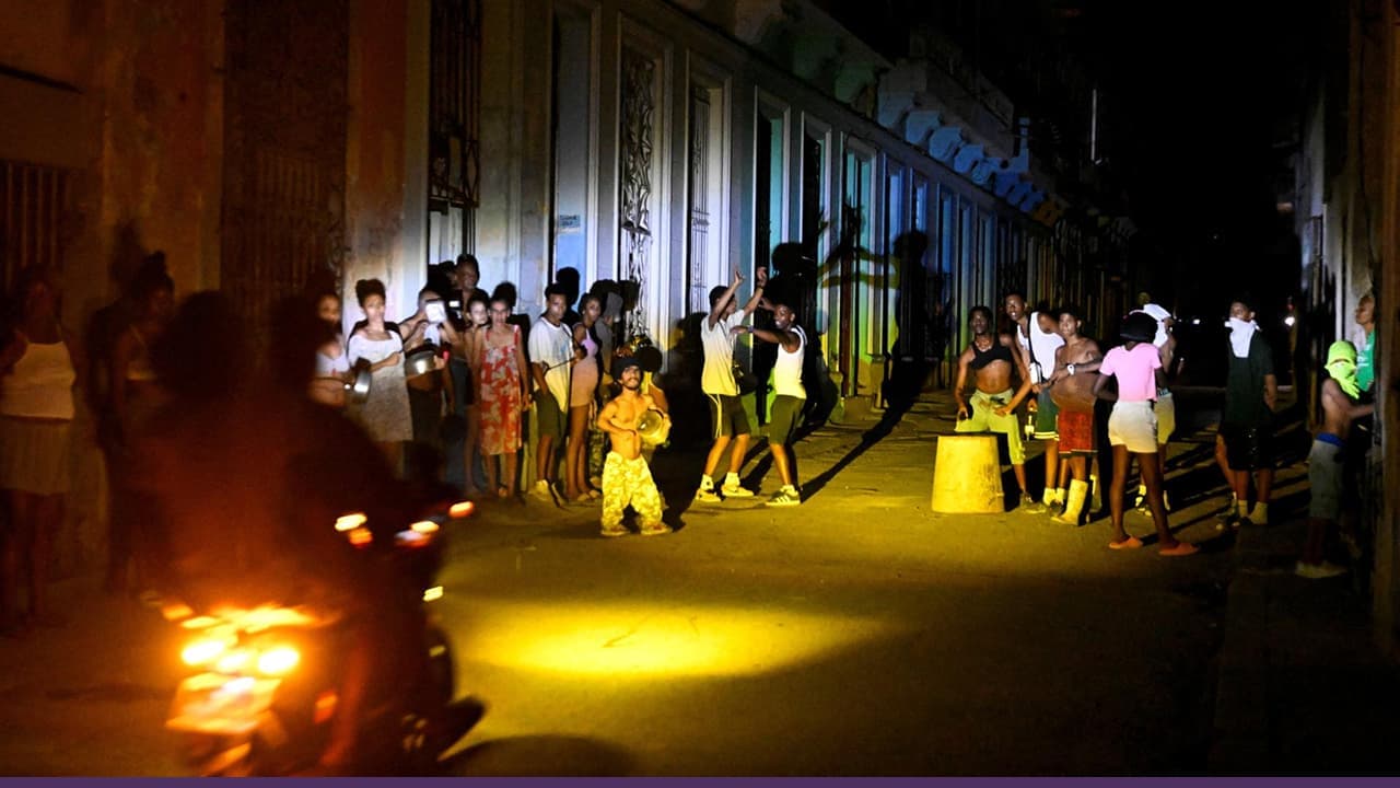 Residents gather on dark street during nationwide power outage
