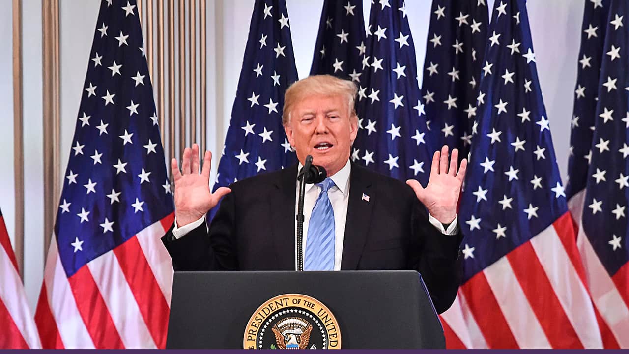 Donald Trump speaking at podium before US flags
