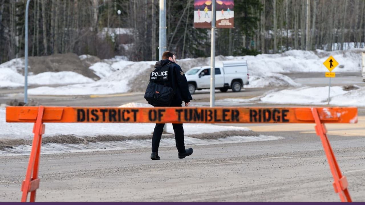 Police officer behind Tumbler Ridge snowy road closure barricade