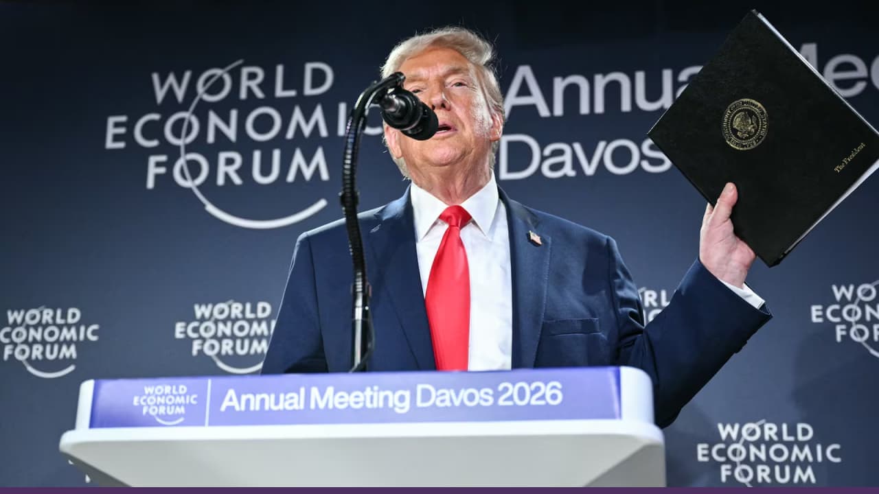 Speaker addressing World Economic Forum podium holding document